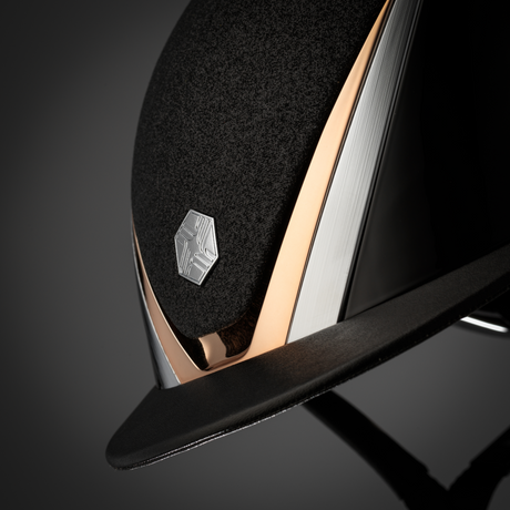 Charles Owen Hyda Sparkly riding hat in Black Gloss/Rose Gold, close-up of the crown and peak on a dark background